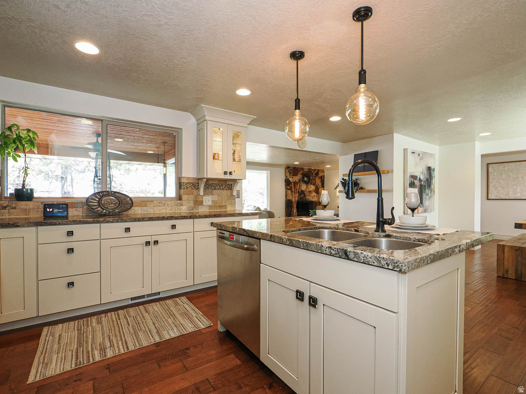 Kitchen featuring an island with dual sinks, cream cabinetry, stone countertops, and wood-finish flooring