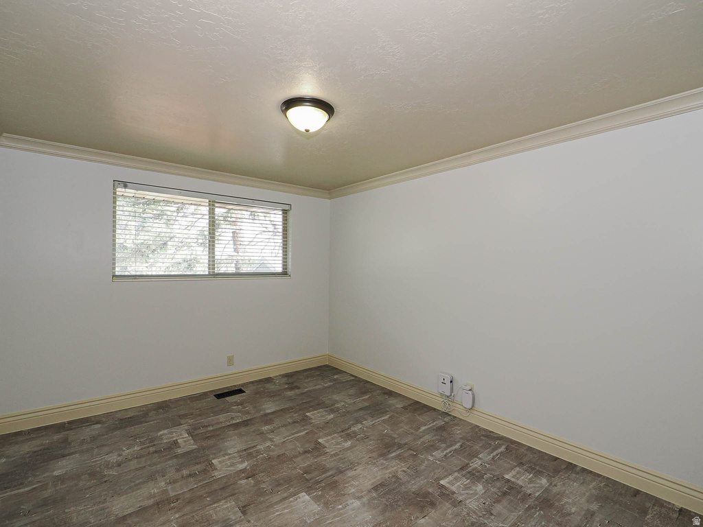 Room featuring wood-finish flooring, white walls, and a window with blinds
