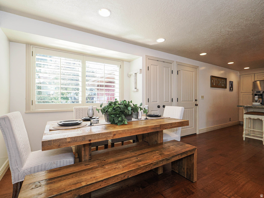 Dining area featuring wood-finish flooring, two panel-style doors with dark hardware, recessed lighting, and a large window with white plantation shutters