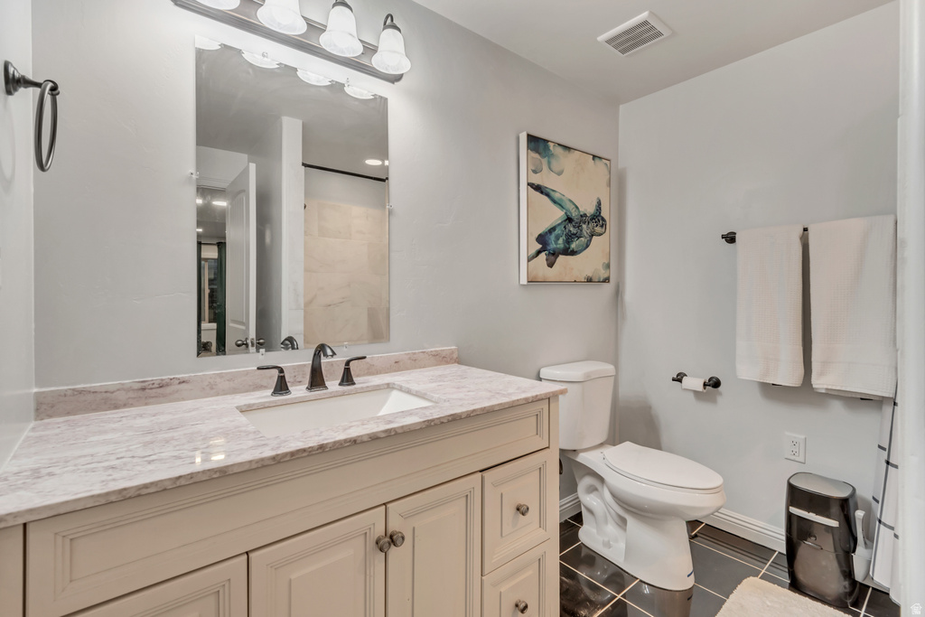 Bathroom featuring a single vanity with integrated sink, stone countertop, and custom cabinetry