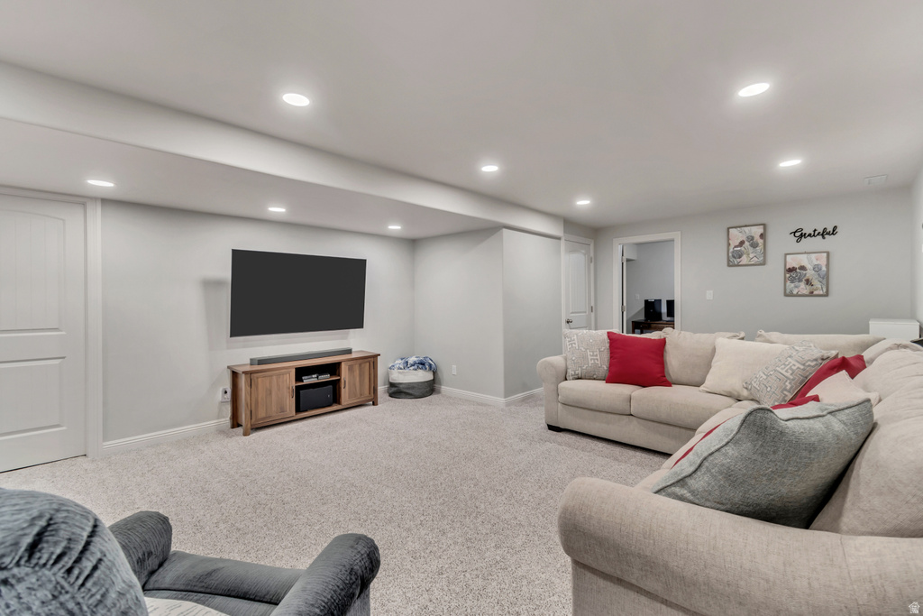 Spacious entertainment area featuring light gray walls, recessed lighting, and soft gray carpeting