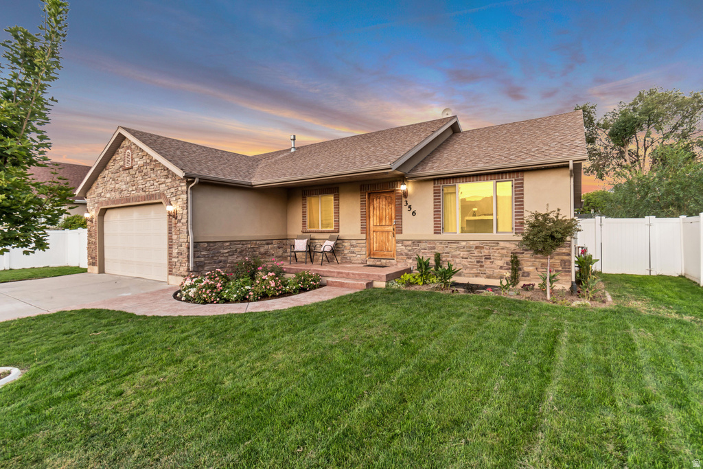Stone and stucco exterior with brick accents, an attached garage, a covered entry, and a fully fenced yard
