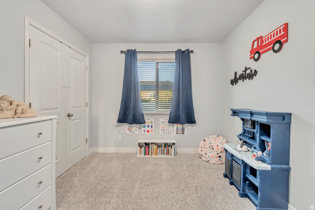 Room featuring light gray walls, gray carpet, a window with blinds and blue curtains, and white baseboards