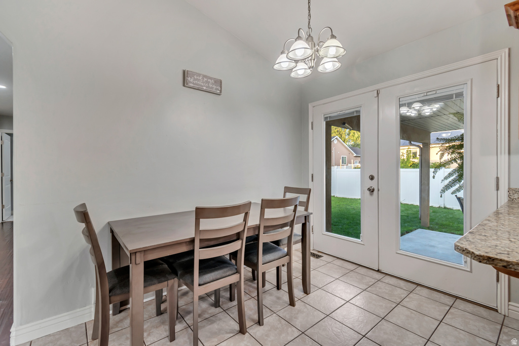 Dining area featuring light tile flooring and a five-light chandelier