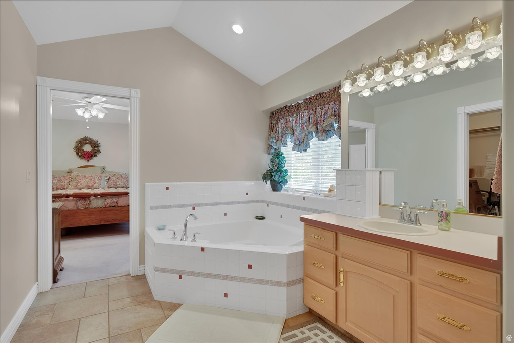 Bathroom featuring a corner soaking tub with tile surround, single vanity with a laminate countertop, and tile flooring