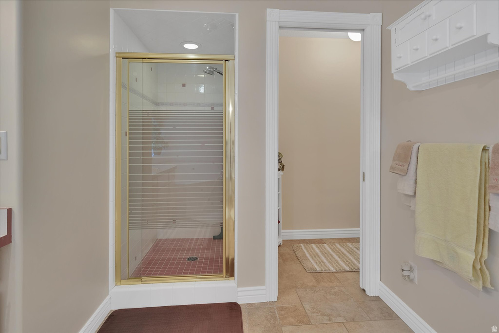 Shower enclosure with gold-finish frame and frosted glass, featuring red square tile flooring
