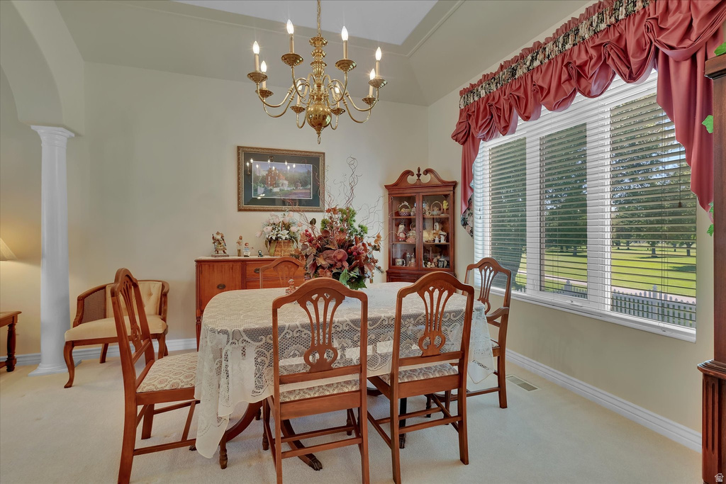 Spacious room featuring a multi-pane window, a brass chandelier, a decorative column, and crown molding