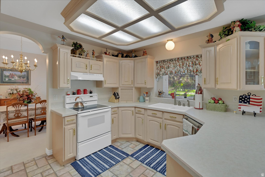 Kitchen featuring light-toned cabinetry, a white electric range, and a double basin sink beneath a window