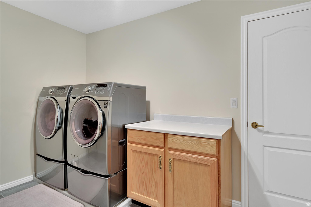 Dedicated laundry area featuring light-toned walls, tile flooring, a built-in wood cabinet with a light-colored countertop, and a classic paneled door with brass hardware