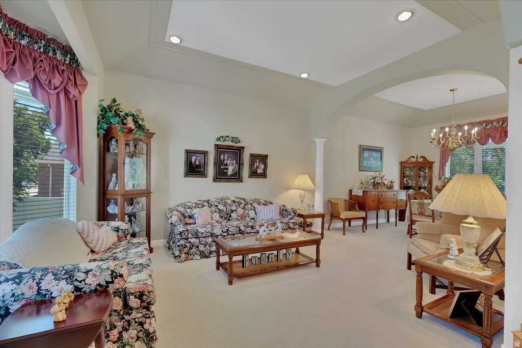 Spacious living area featuring a tray ceiling with recessed lighting, an arched entryway, and carpet flooring