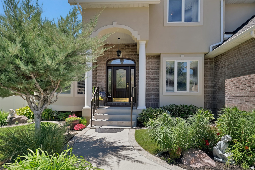 Stucco and brick exterior featuring a covered entry, arched doorway, decorative columns, and a bay window