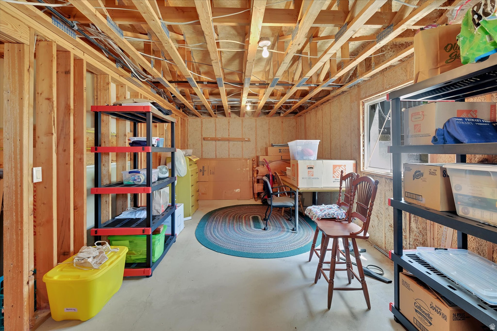 Unfinished basement space featuring exposed wooden joists, framed walls, a window opening, and a concrete floor