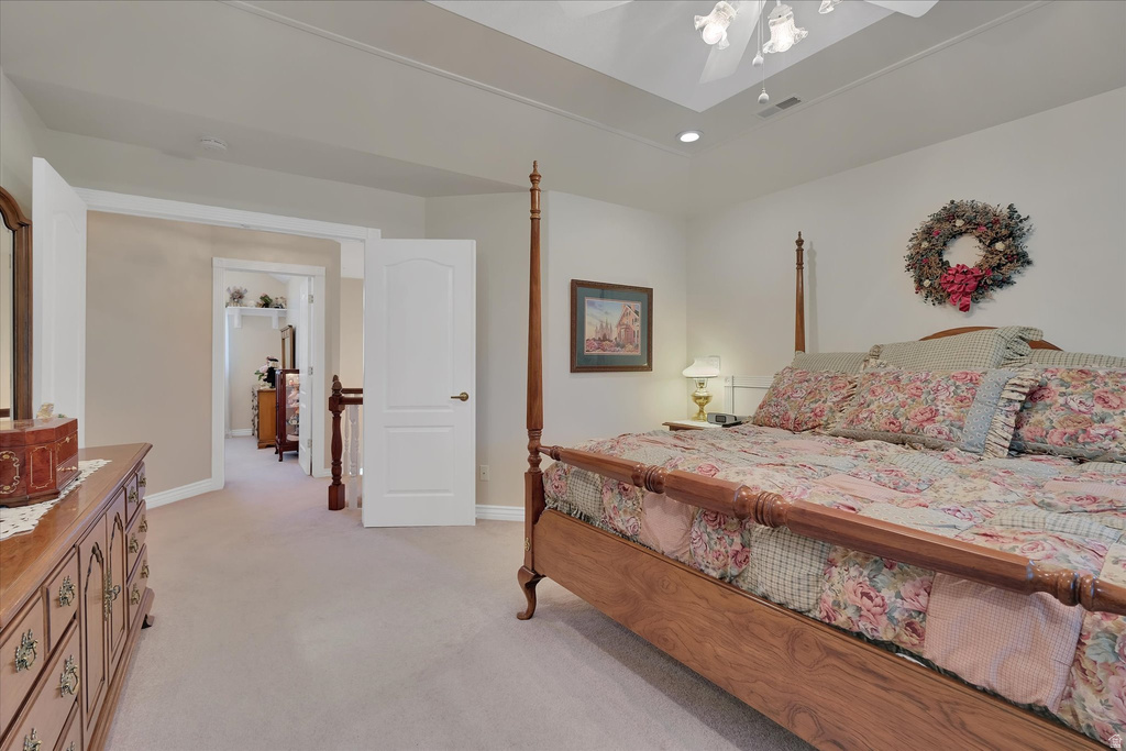 Carpeted bedroom featuring a tray ceiling with recessed lighting, white trim, and a white ceiling fan