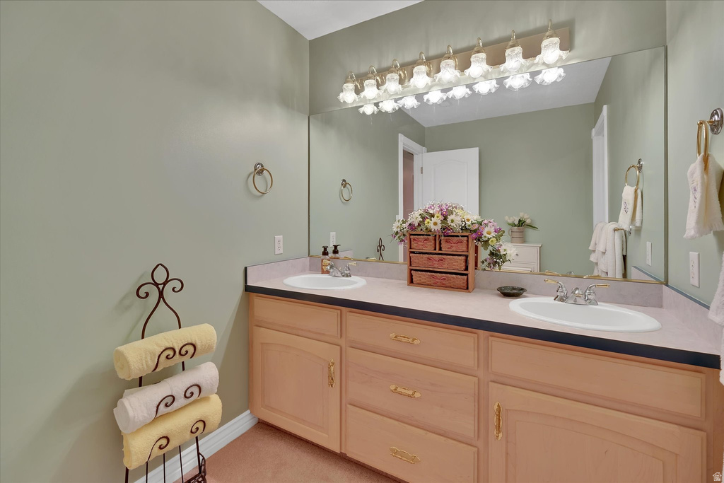 Double vanity with light wood-finish cabinetry and gold-tone hardware