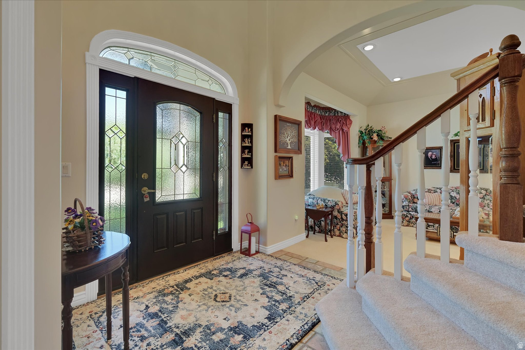 Foyer featuring a dark wood entry door with decorative glass panels and an arched transom window