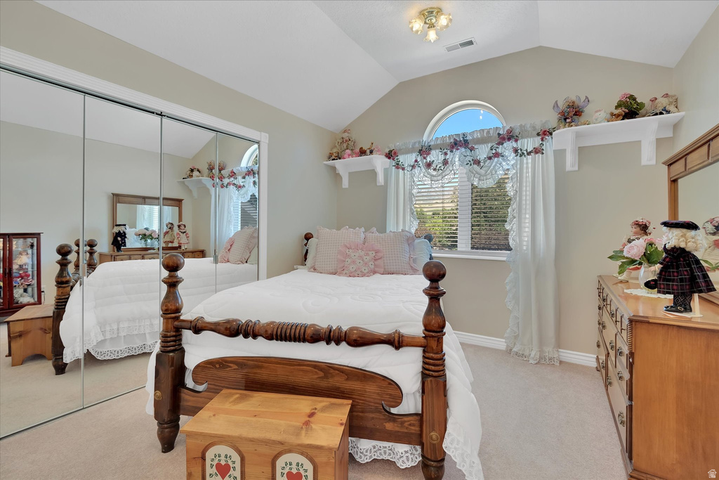 Vaulted ceiling bedroom featuring an arched window, carpet flooring, a ceiling-mounted light fixture, and mirrored sliding closet doors