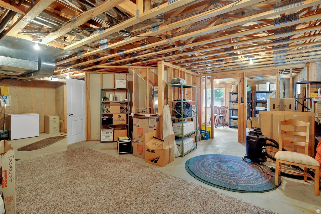 Expansive unfinished basement featuring visible wood framing, exposed ductwork, and partial carpeting
