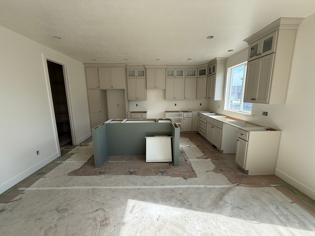 Kitchen featuring extensive cabinetry, a central island structure, recessed lighting, and a pantry with built-in shelving