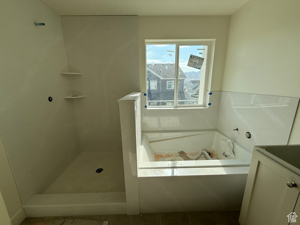 Tiled walk-in shower with built-in shelving, integrated bathtub, and a window with a mountain backdrop