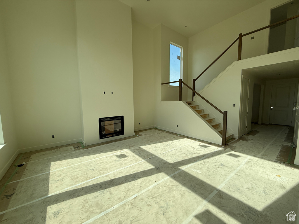 Two-story living area with an integrated fireplace, a full staircase with wood railings, a tall ceiling, and large windows
