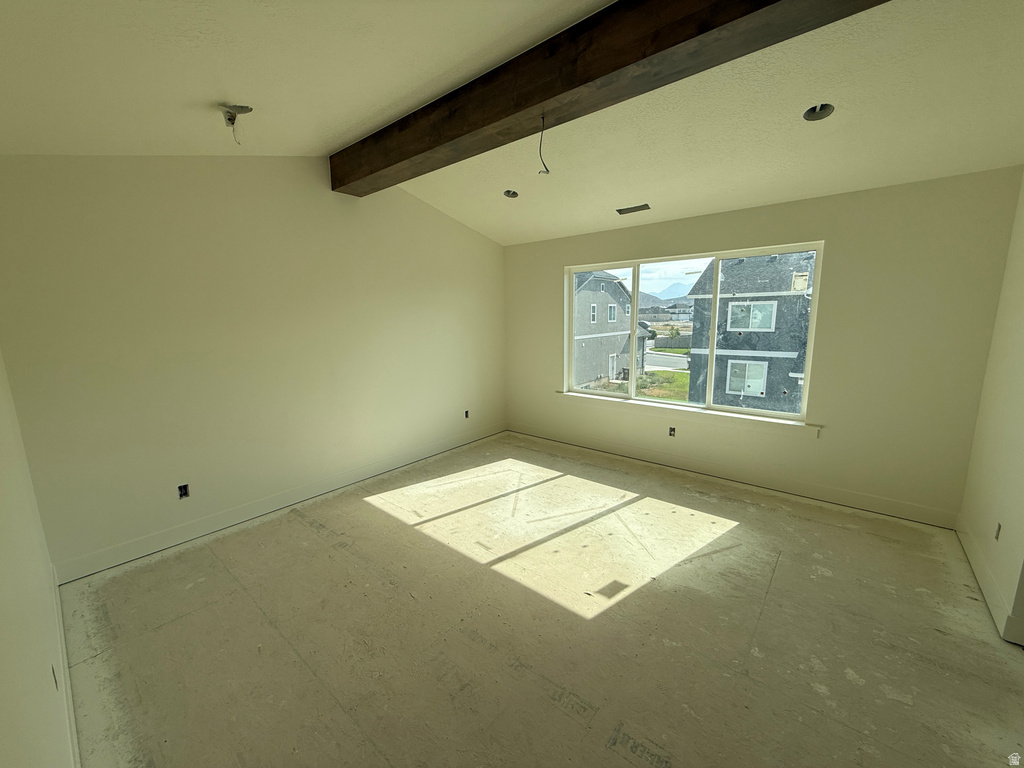 Vaulted ceiling with an exposed wood beam, large window, and recessed lighting