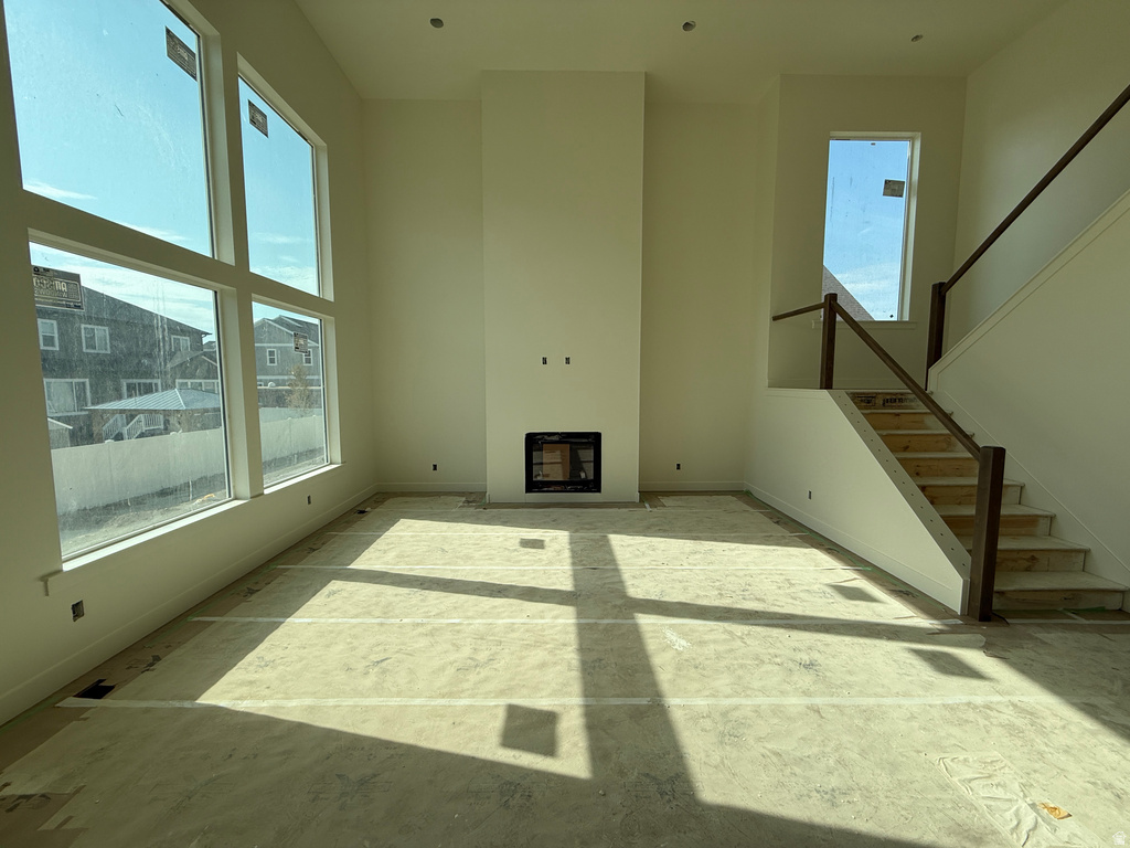 Two-story living area with expansive windows, a built-in fireplace, and a staircase featuring wood-finish railings