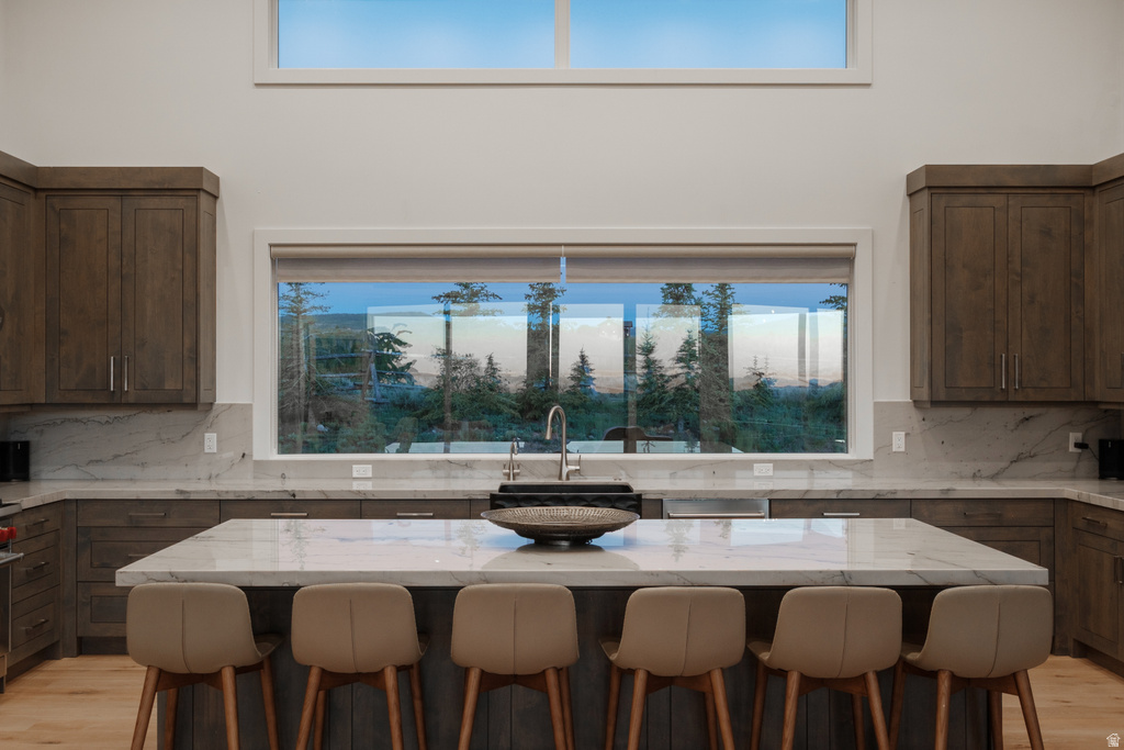 Spacious kitchen featuring an expansive central island with seating, extensive wood cabinetry, marble-finish countertops, and a large picture window