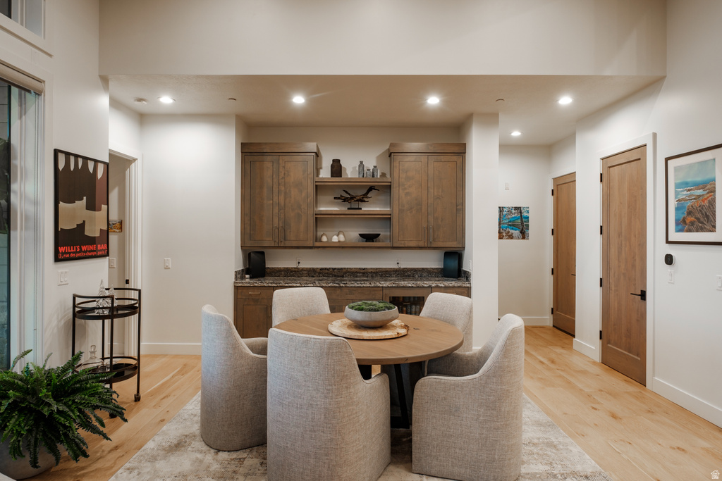 Built-in wet bar featuring upper and lower cabinetry, open shelving, and a stone countertop