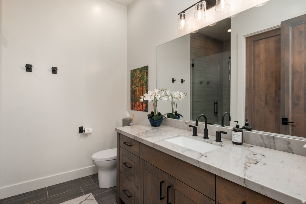 Spacious bathroom featuring a single vanity with a rectangular undermount sink, a stone-finish countertop with natural veining, and a dark wood-finish cabinet with matte black hardware