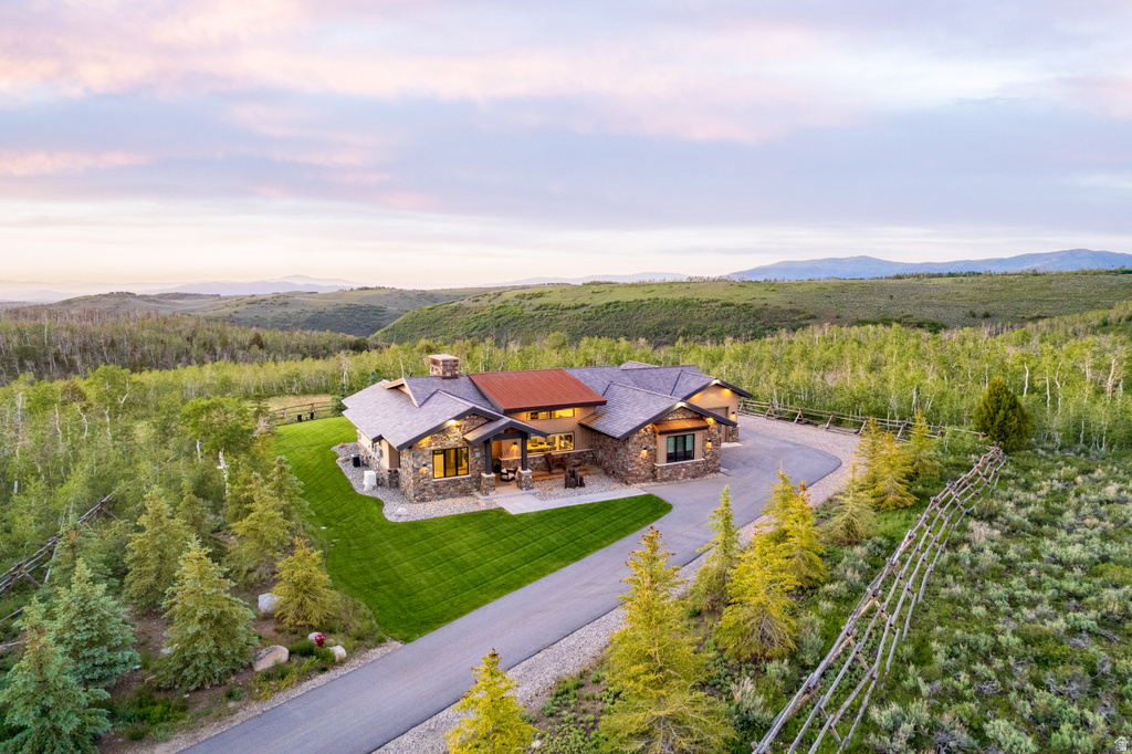 Stone and wood-sided residence featuring a multi-gabled roofline and an expansive paved driveway