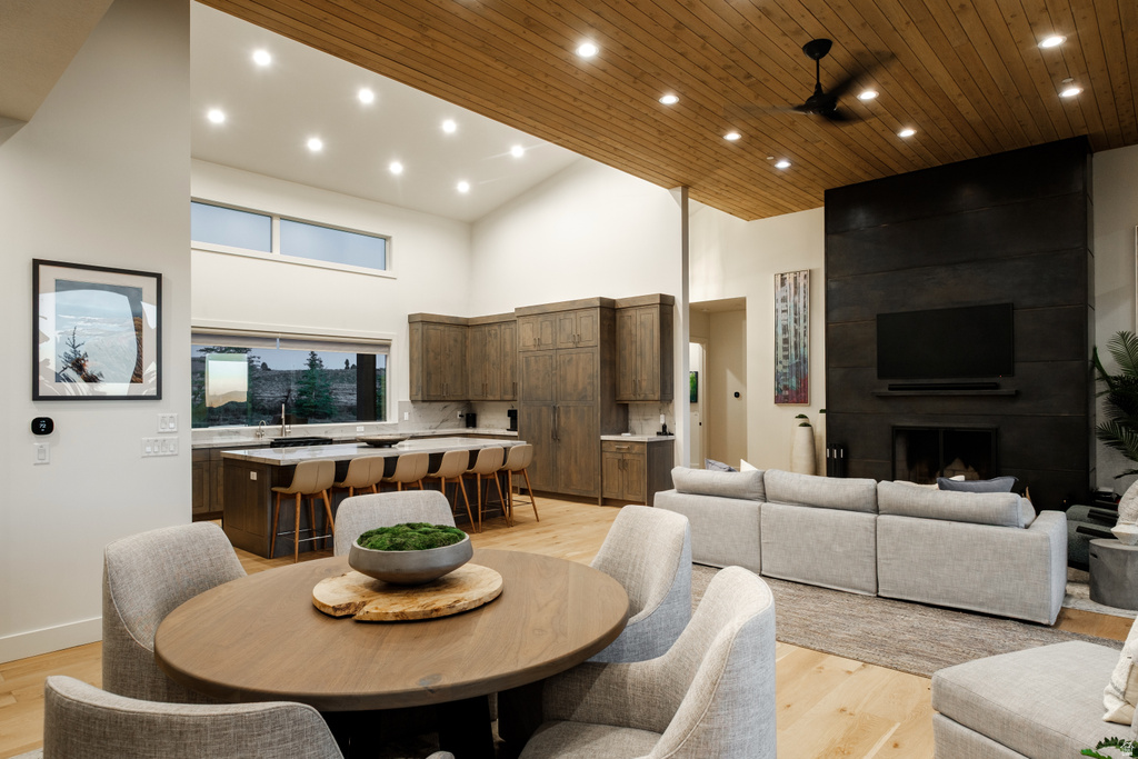 Open-concept living space featuring wood-finish flooring, a wood-paneled ceiling, and a prominent dark-paneled fireplace