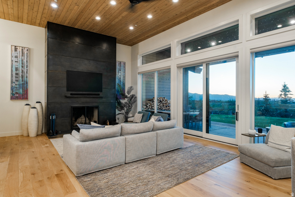 Spacious living area featuring a floor-to-ceiling fireplace with an integrated media niche, wood-finish flooring, and a wood-paneled ceiling