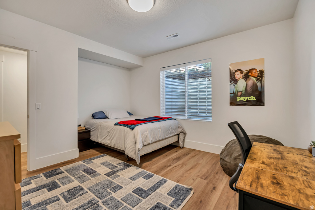 Bedroom featuring wood-finish flooring, white walls, and a recessed ceiling light