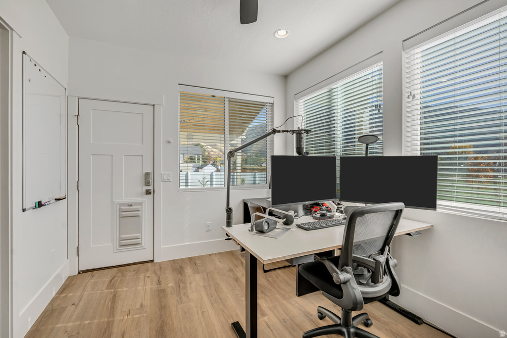 Bright interior space featuring wood-finish flooring, white walls, and multiple windows with blinds