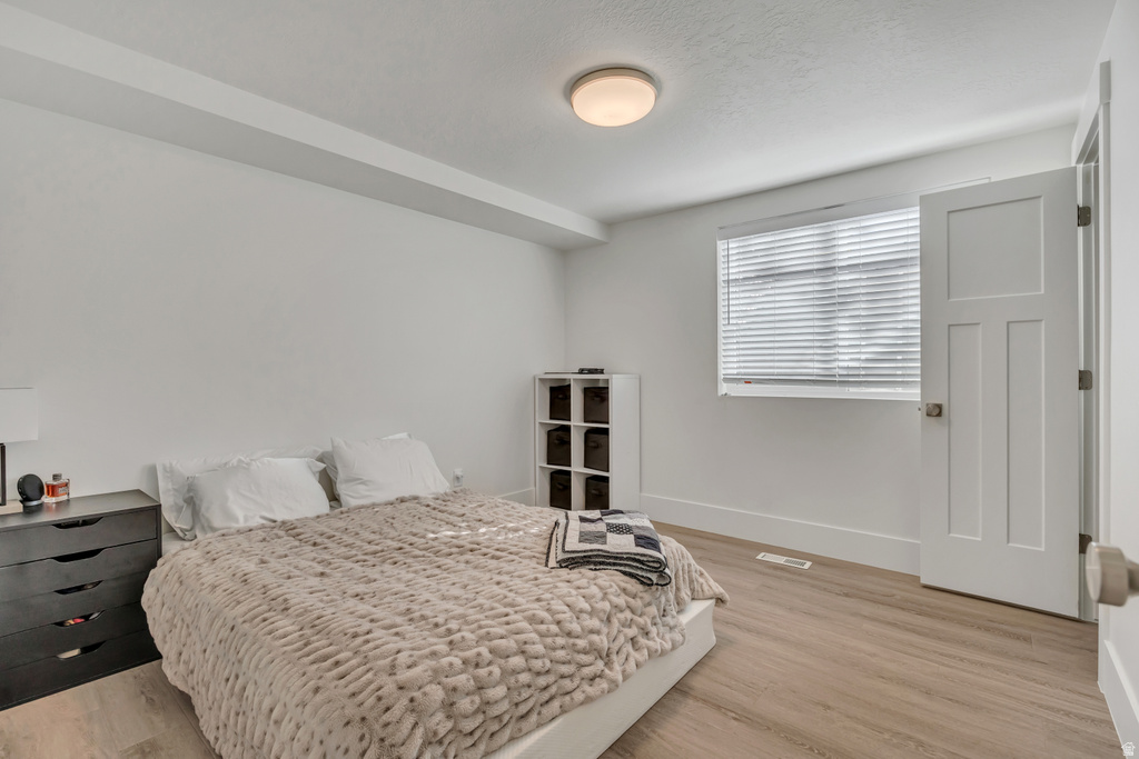 Bright room featuring wood-finish flooring, a contemporary flush-mount ceiling light, and a window with horizontal blinds