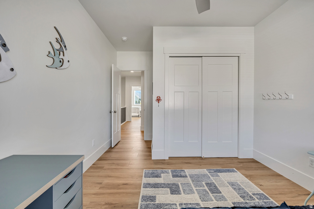 Room featuring wood-finish flooring, white walls, and a white sliding closet door