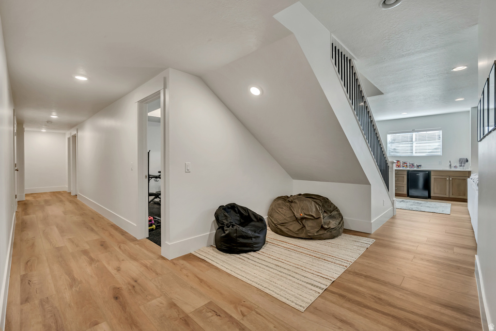 Lower level featuring light wood-finish flooring, recessed lighting, and a built-in wet bar with cabinetry and an under-counter refrigerator