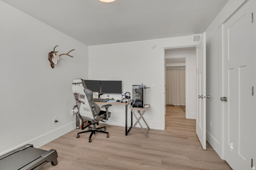 Spacious room with light wood-finish flooring, white walls, and bright overhead lighting