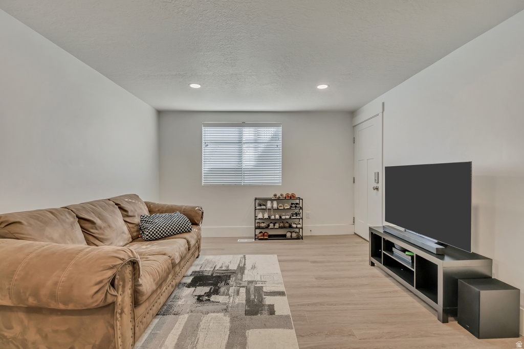 Spacious interior room featuring light-toned wood-finish flooring, recessed lighting, and a window with blinds
