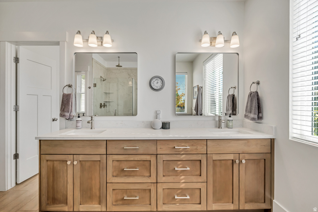 Double vanity with light wood-finish cabinetry, white countertop, and brushed nickel hardware