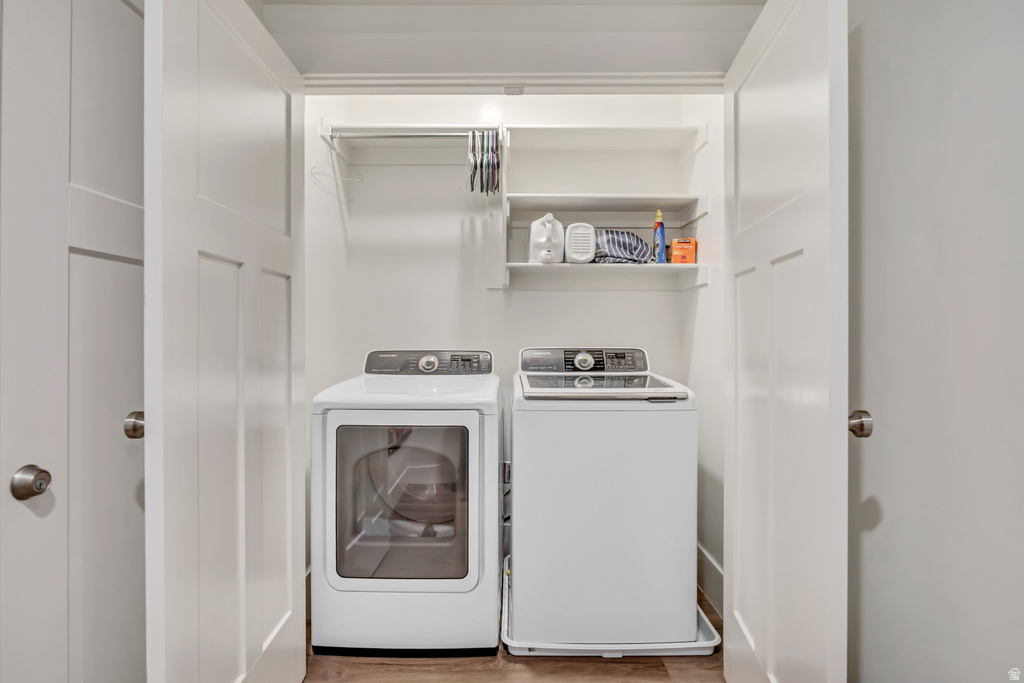 Dedicated laundry closet featuring a built-in shelf, clothing rod, and wood-finish flooring