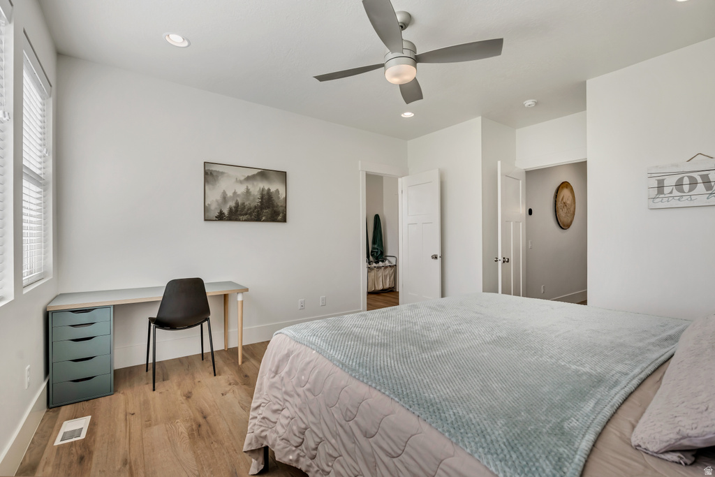 Light wood-finish flooring with white baseboards, recessed lighting, and a ceiling fan