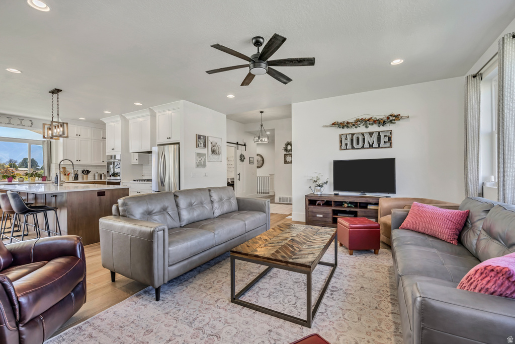Open-concept living space featuring wood-finish flooring, a contemporary ceiling fan, and recessed lighting