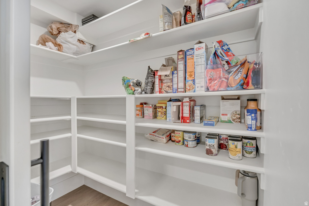 Walk-in pantry featuring extensive white shelving and wood-finish flooring