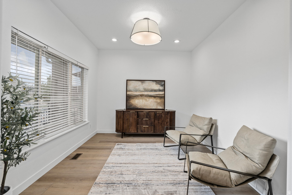 Bright room featuring a wide window with horizontal blinds, wood-finish flooring, recessed lighting, and a drum pendant light fixture
