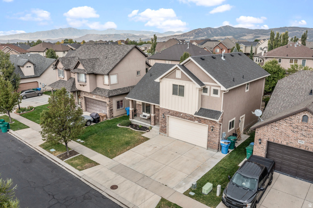 Two-story residence featuring a two-car garage, stone and stucco exterior, and a covered porch