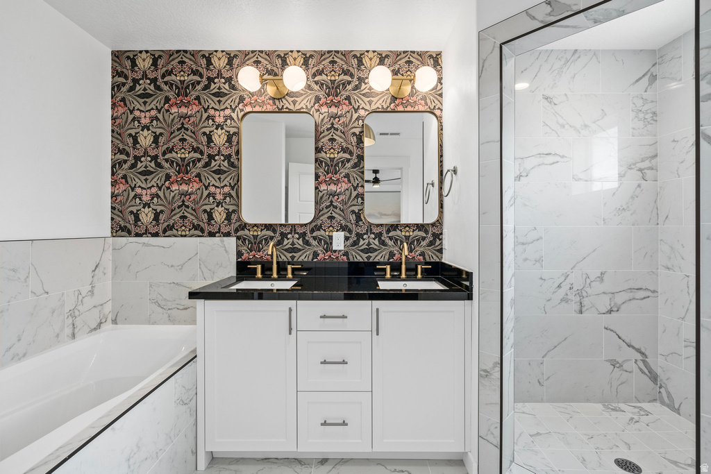 Modern bathroom featuring a dual vanity with white cabinetry, black countertops, and brass fixtures