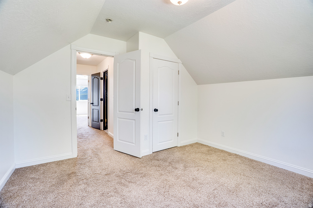 Carpeted room featuring white walls and sloped ceilings