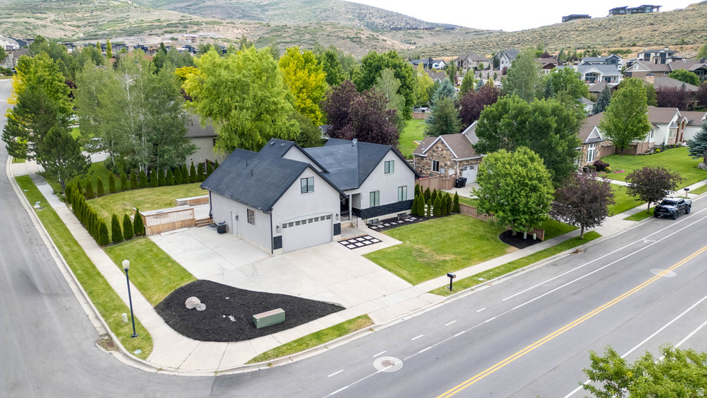Contemporary-style residence featuring a two-car garage, manicured front lawn, and mature perimeter trees