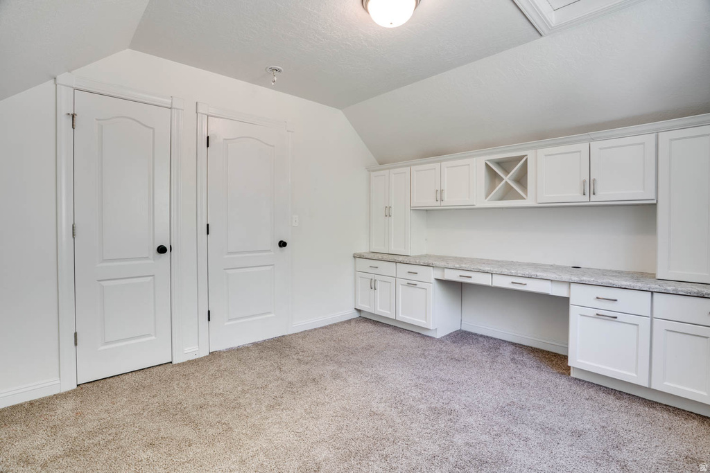 Built-in desk area featuring extensive white cabinetry, a built-in wine rack, and a light-toned countertop